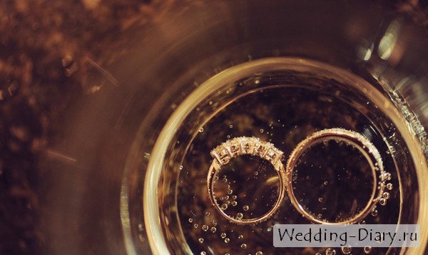 Оригинальная идея - обручальные кольца на дне бокала с шампанским Кольцо невесты с камнями, жениха - гладкое