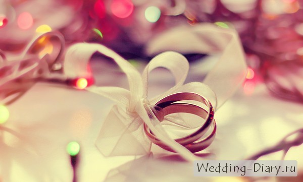 Свадебные кольца связаны ленточкой Фото колец на фоне гирлянды - идея для новогодней свадьбы