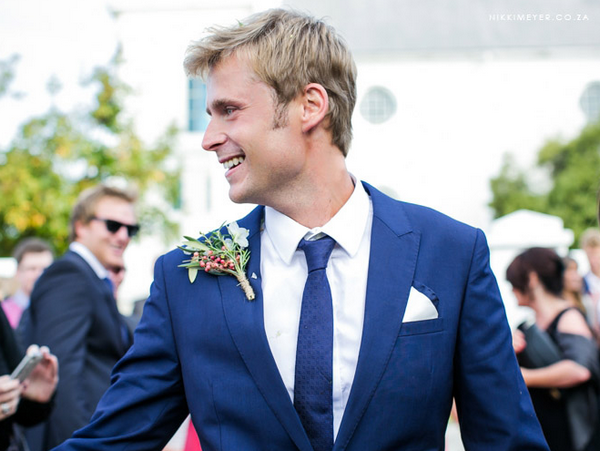 Стильный жених в синем костюме с бутоньеркой